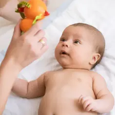 Co widzi tygodniowe dziecko? Zaciekawiony noworodek patrzy na kolorową zabawkę trzymaną przez mamę.