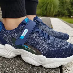 Granatowe buty sportowe dla dziecka z rzepem i sznurówkami. Dowiedz się, ile większe powinny być buty dla dziecka, by zapewnić komfort.