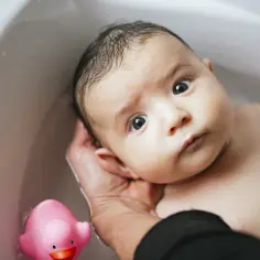 Niemowlę w wannie z różową kaczką. Czy można kąpać niemowlę z gorączką? Delikatna kąpiel w wannie.