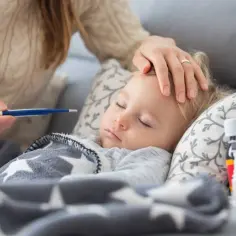 Chora dziewczynka śpi, mama mierzy jej temperaturę. Zastanawiasz się, ile bierze opiekunka do dziecka za noc?