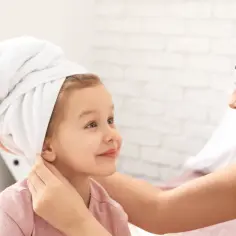 Mama pomaga dziecku z ręcznikiem na głowie. Chcesz wiedzieć, co zrobić, aby dziecku zgęstniały włosy?