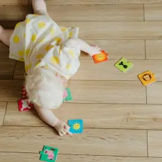 Dziecko leży na brzuchu, bawiąc się puzzlami ze zwierzątkami. Czy dziecko może spać na brzuchu? To pytanie nurtuje wielu rodziców.