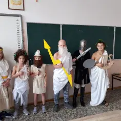 Dzieci w strojach bogów greckich: Zeus z piorunem, Hades w zbroi, Apollo z lirą. Świetny pomysł, jak przebrać dziecko za boga greckiego!
