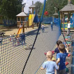 Dzieci bawią się na placu zabaw w parku linowym, pokonując przeszkody.