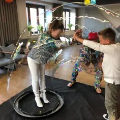 Dzieci i dorośli tworzą bańkę mydlaną, doświadczając magicznego zamykania w bance mydlanej.