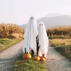 Dzieci w przebraniu babci na Halloween, stoją na drodze wśród pól kukurydzy.