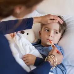 Mama mierzy temperaturę choremu synkowi. Czy można kąpać dziecko gdy ma gorączkę?
