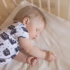 Śpiące niemowlę na brzuchu w łóżeczku. Czy niemowlę może spać na brzuchu po jedzeniu? Bezpieczny sen to podstawa.