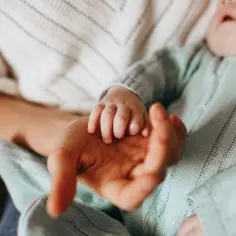 Dłoń dziecka w dłoni rodzica. Czas pomyśleć, jak zapisać dziecko do żłobka, by zapewnić mu opiekę i rozwój.