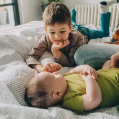 Starszy brat patrzy z czułością na niemowlę. Zastanawiamy się, ile rosną dzieci w ciągu roku, obserwując ich rozwój.