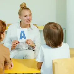 Nauczycielka pokazuje dzieciom literę "A", ucząc je podstaw, jak w statucie przedszkola.