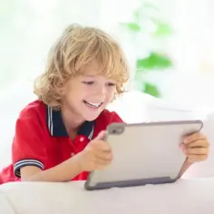 Uśmiechnięty chłopiec z tabletem. Czy zastanawiasz się, jak usunąć kontrolę rodzicielską na telefonie dziecka?