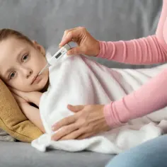 Mama mierzy temperaturę chorej córce. Warto wiedzieć, jak podawać leki przeciwgorączkowe dziecku, by szybko poczuło ulgę.