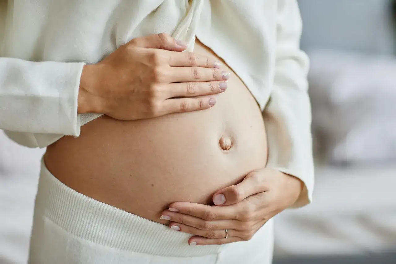 Czułe dłonie obejmujące ciążowy brzuch. Zastanawiasz się, ile powinno być ruchów dziecka na godzinę?