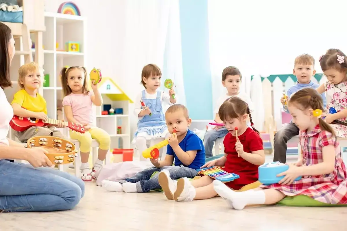 Dzieci w przedszkolu, w wieku od 3 do 6 lat, bawią się instrumentami. Wszyscy świetnie się bawią, ucząc się, ile lat ma się w przedszkolu.