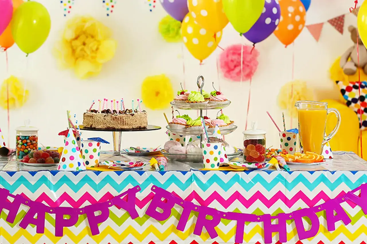 Kolorowy stół na roczek: tort, babeczki, słodycze, balony i napój. Idealnie, co się kładzie na roczek na stole!