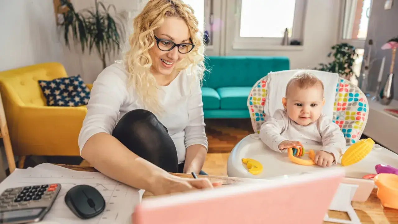 Pracująca mama z dzieckiem przy biurku. Czy można rozliczyć się z pracującym dzieckiem? Tak, gdy jest się tak zorganizowanym jak ona.