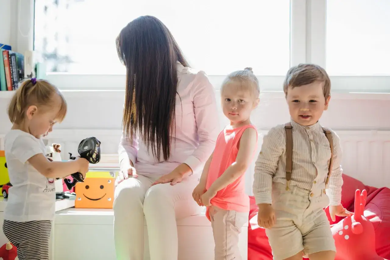 Opiekunka z dziećmi w pokoju zabaw. Zastanawiasz się, ile zarabia opiekunka na godzinę?