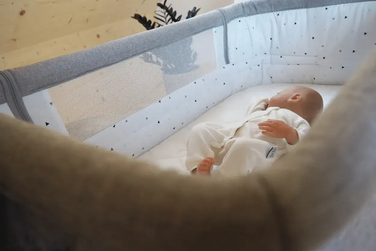 Niemowlę śpi na brzuchu w łóżeczku. Ważne jest, jak długo niemowlę może spać na brzuchu, by zapewnić mu bezpieczeństwo.