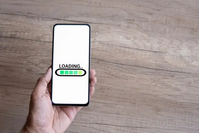 Dłoń trzyma smartfon z ekranem ładowania. Czas na odinstalowanie aplikacji kontrola rodzicielska.